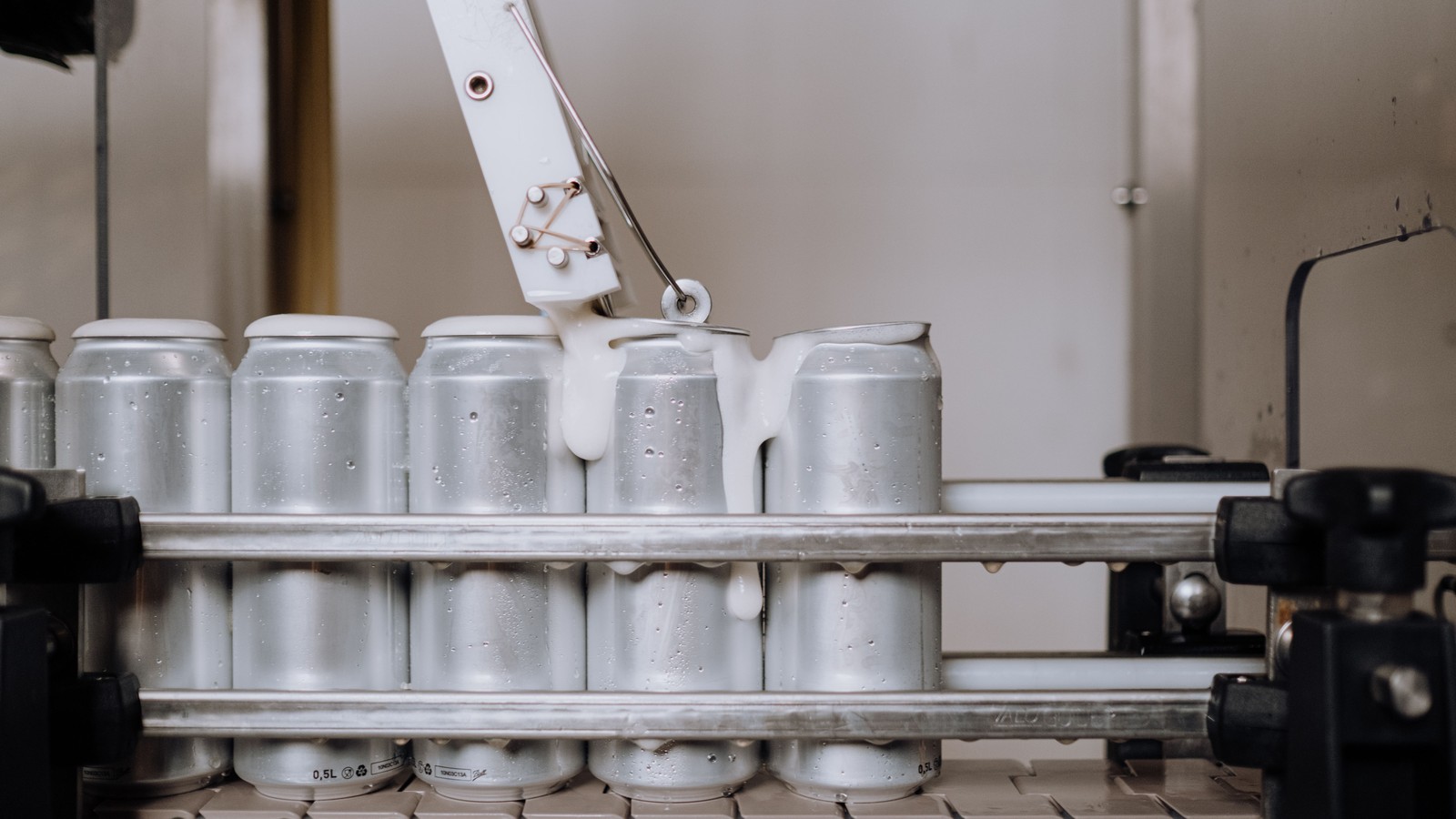 Latas de aluminio avanzando por una cinta transportadora en una línea de producción