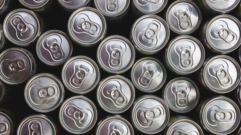 Vista superior de latas de aluminio apiladas, mostrando sus tapas metálicas