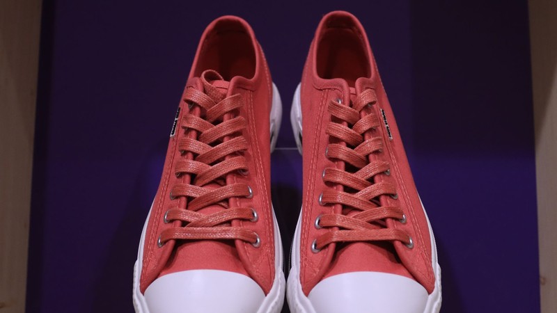 Un par de zapatillas de lona rojas con suela blanca sobre fondo violeta