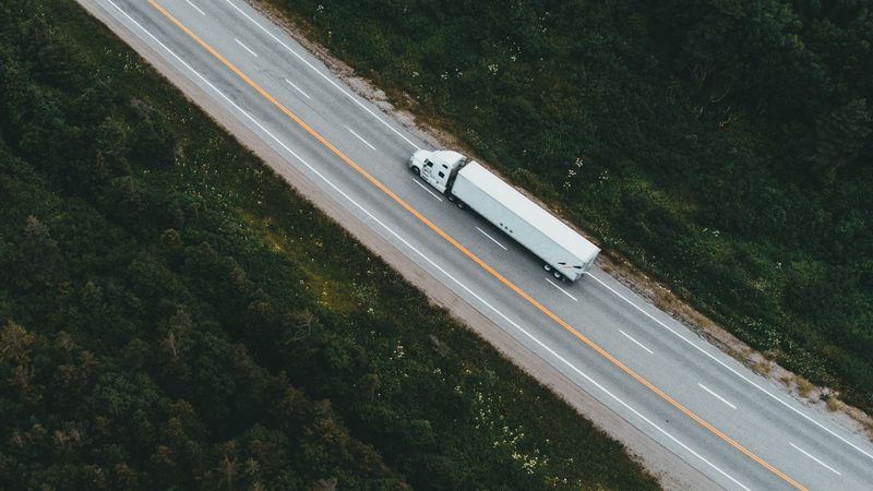 Vista aérea de un camión de carga en una ruta rodeada de bosque
