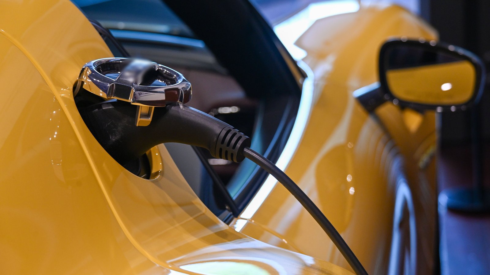 Cable de carga conectado a un auto eléctrico amarillo