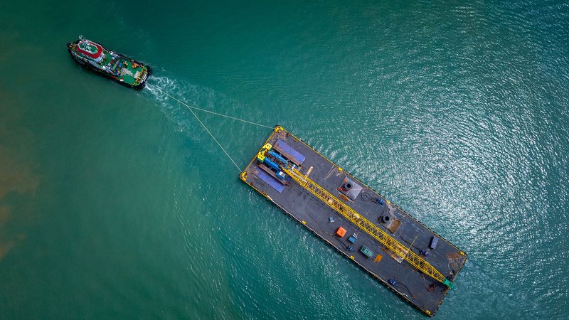 Vista aérea de un remolcador trasladando una barcaza de carga por el mar