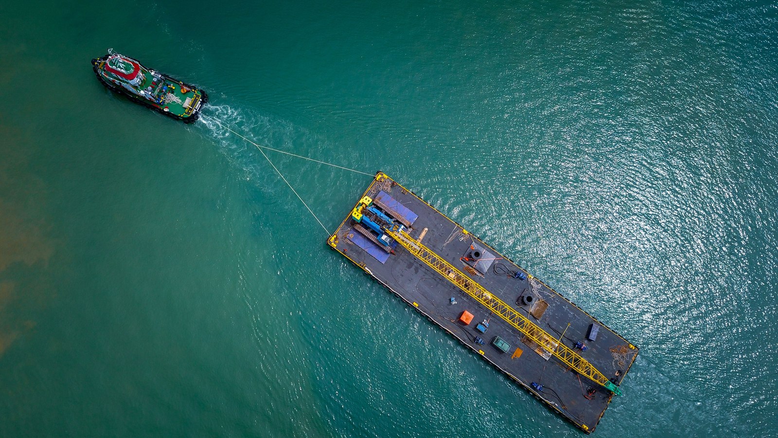 Vista aérea de un remolcador trasladando una barcaza de carga por el mar