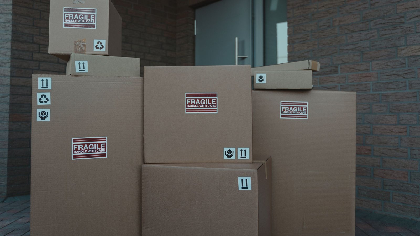 Cajas de cartón con etiquetas de frágil apiladas en la entrada de una casa