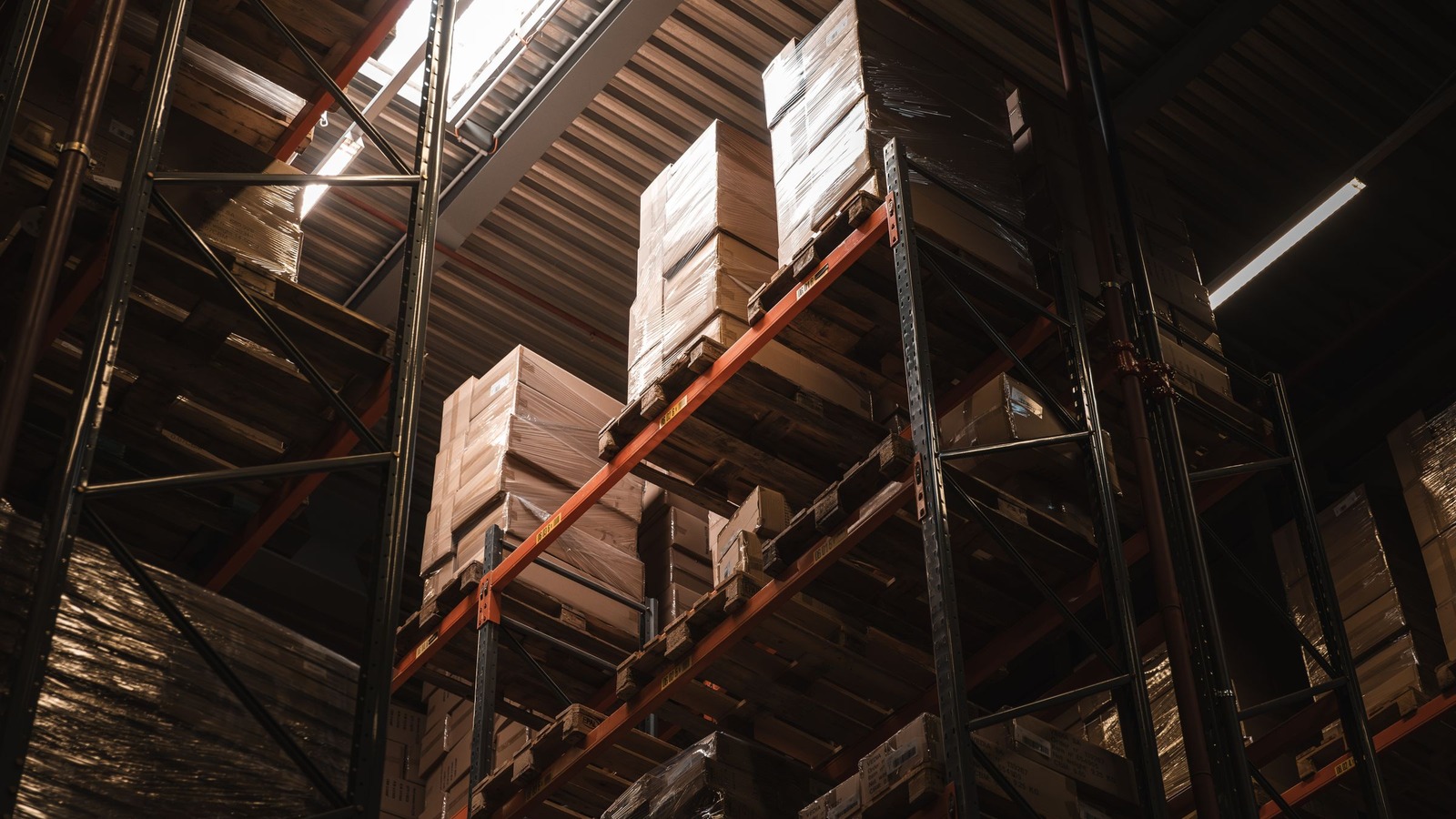 Estanterías industriales altas con cajas apiladas en un depósito, en contrapicado