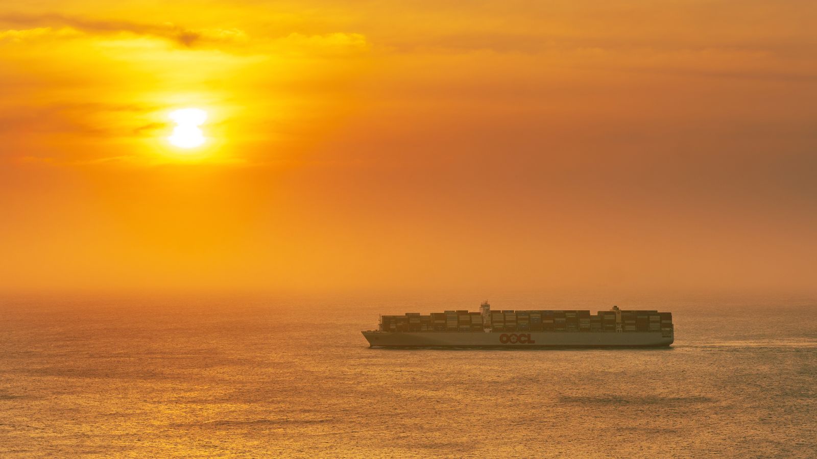 Buque portacontenedores navegando en mar abierto durante un atardecer, ejemplo de transporte marítimo internacional