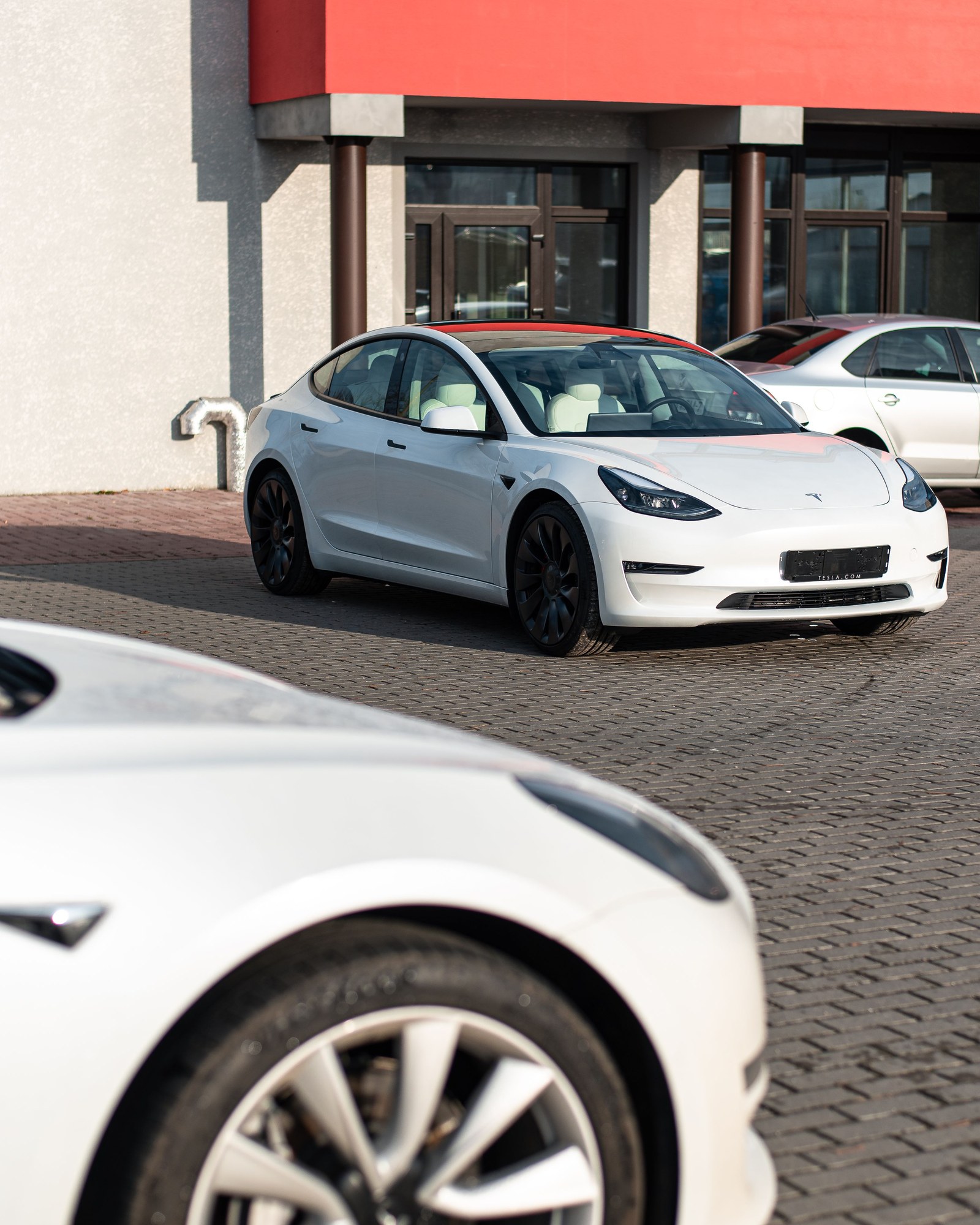 Auto Tesla Model 3 blanco circulando por una avenida