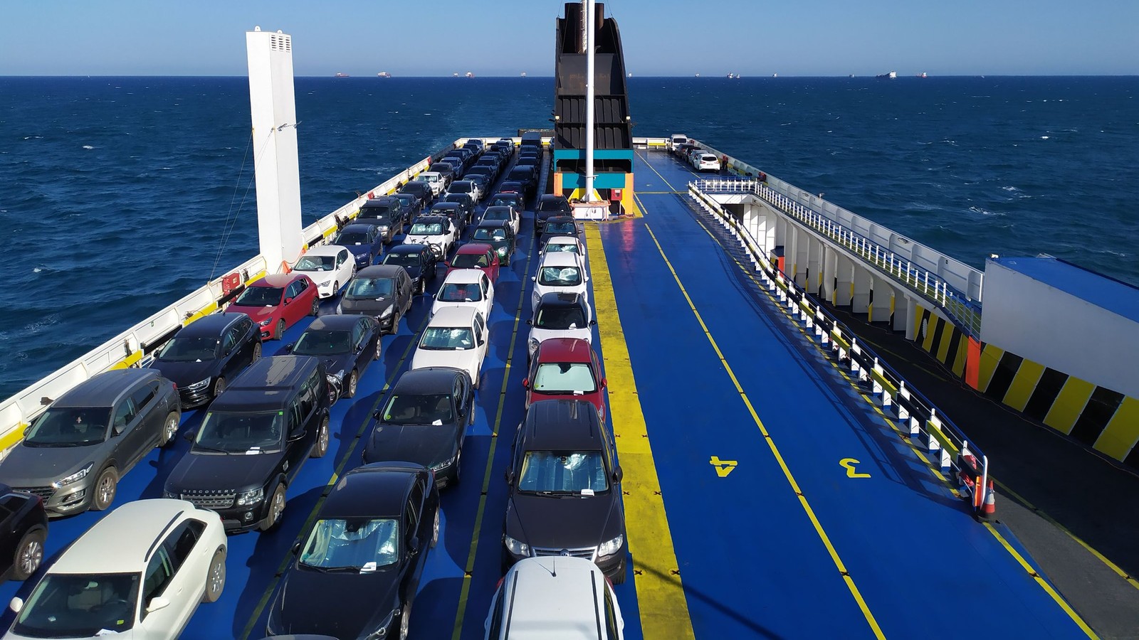 Vista aérea de la cubierta de un buque cargada de autos 0km, con el mar de fondo