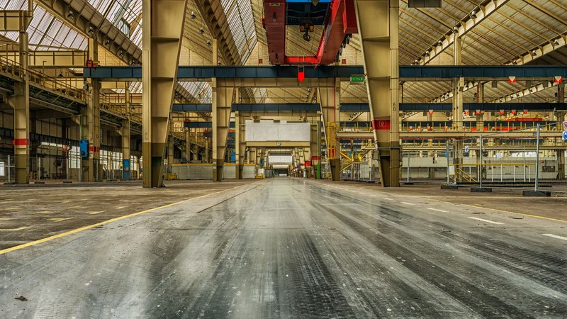 Nave industrial amplia y vacía con estructura metálica y una grúa puente en el techo