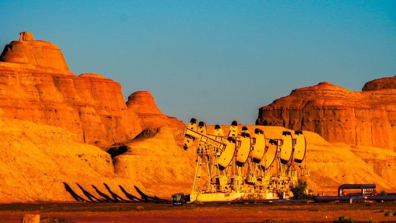 Bombas de extracción de petróleo funcionando en un paisaje desértico de rocas anaranjadas al atardecer