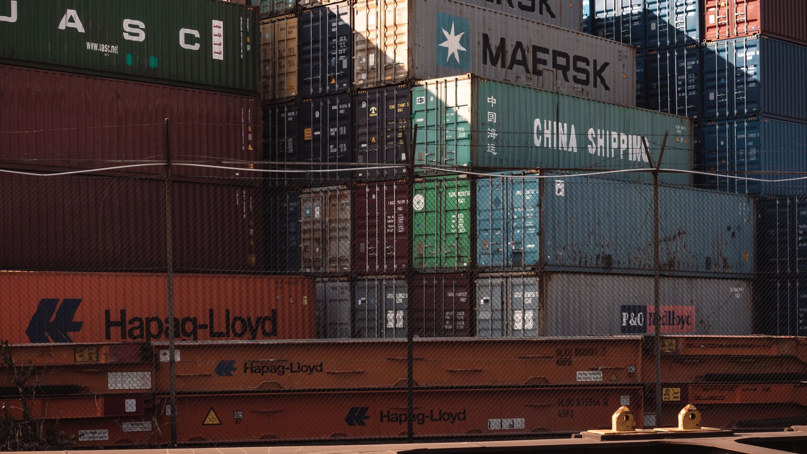 Contenedores de navieras como Maersk, Hapag-Lloyd y China Shipping apilados en una terminal portuaria, ejemplo del comercio marítimo internacional