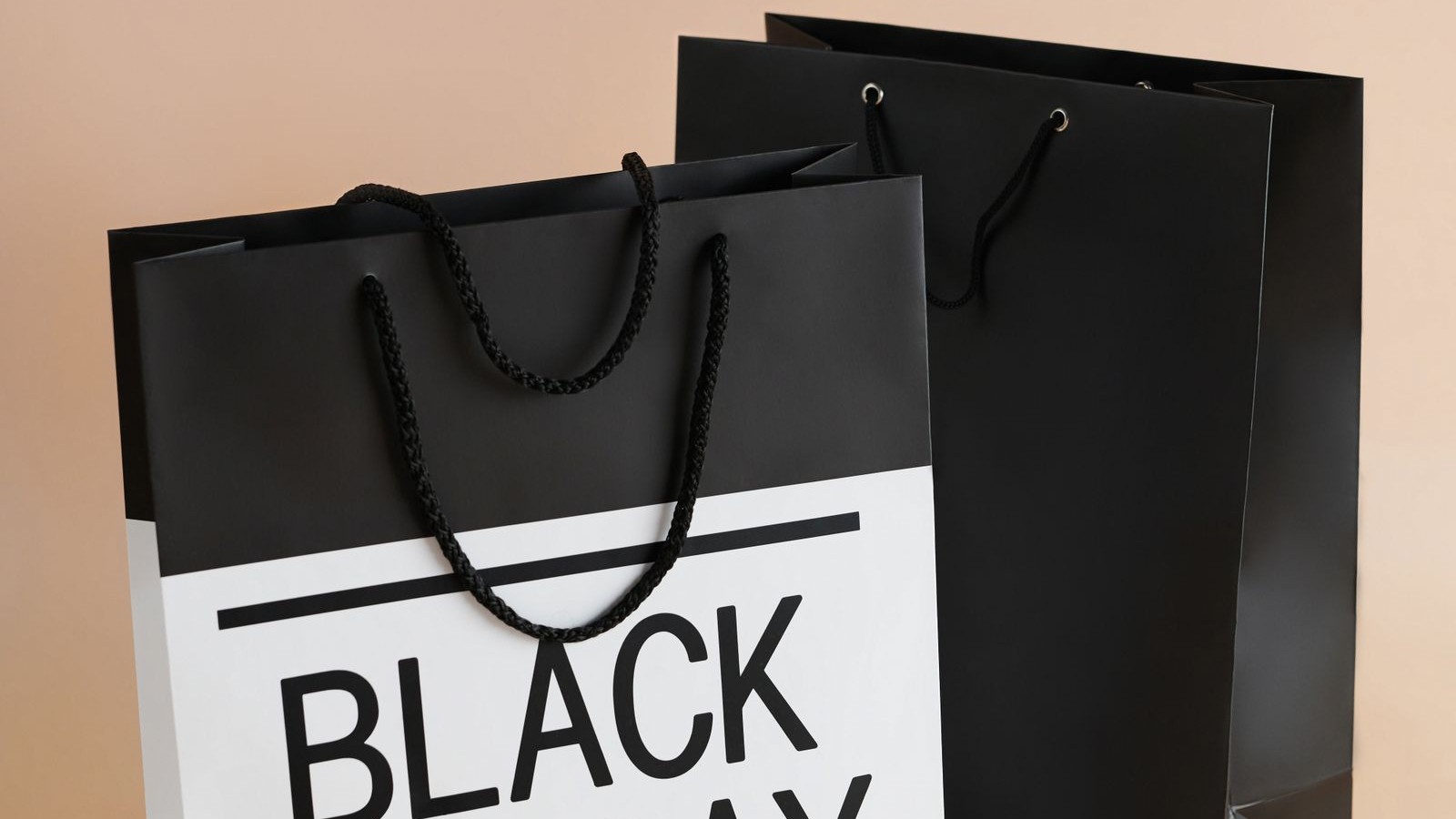 Dos bolsas de compras de papel negras sobre un fondo color durazno